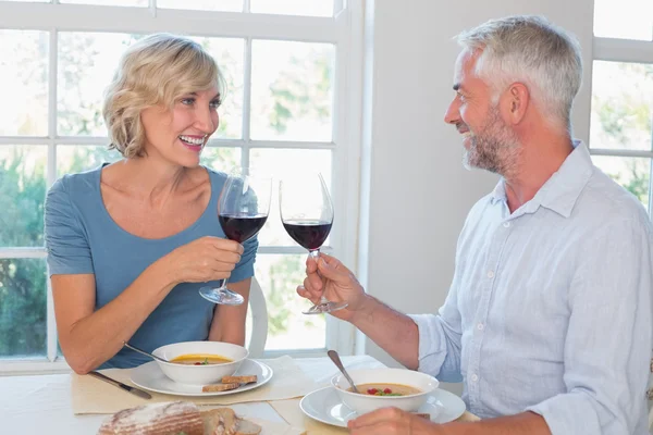 Feliz pareja madura tostando copas de vino sobre la comida — Foto de Stock