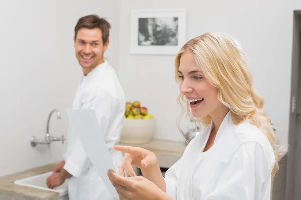 Mujer sorprendida mirando documento con el hombre en la cocina — Foto de Stock