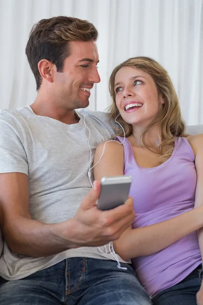 Couple listening music with mobile phone on couch — Stock Photo, Image