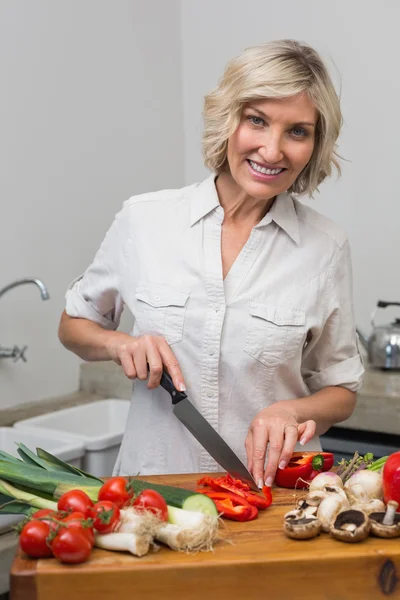 Mulher madura cortando legumes na cozinha — Fotografia de Stock