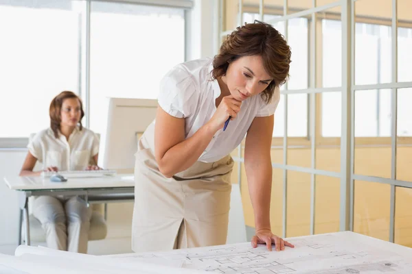 Geschäftsfrau arbeitet mit Kollegin im Hintergrund an Entwürfen — Stockfoto