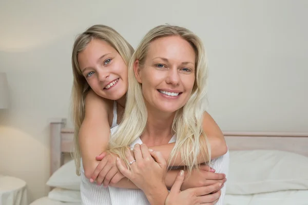 Flicka embracing mor bakifrån i sängen — Stockfoto