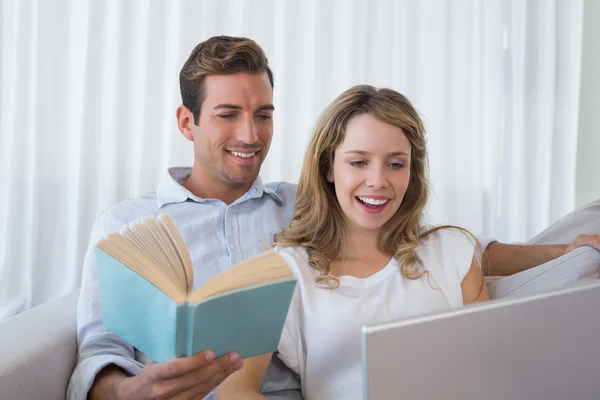 Relaxado amoroso jovem casal com livro e laptop — Fotografia de Stock