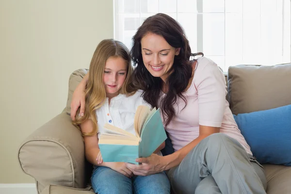 Мать и дочь читают книгу на диване — стоковое фото