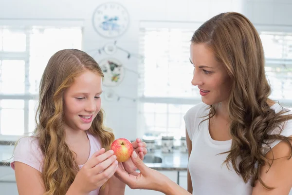 Mamma ger apple sin dotter i köket — Stockfoto