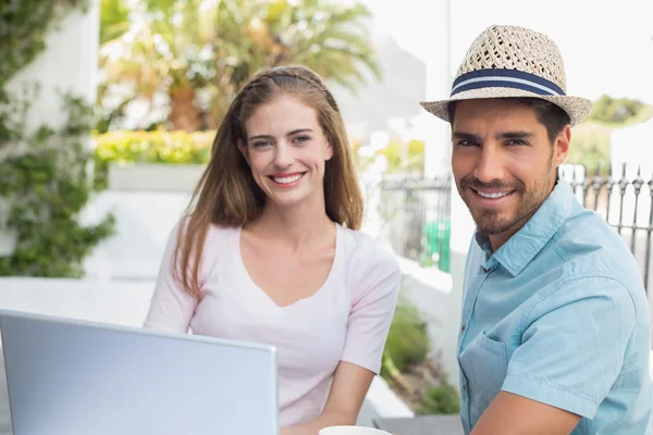 Sorridente giovane coppia utilizzando il computer portatile al caffè — Foto Stock