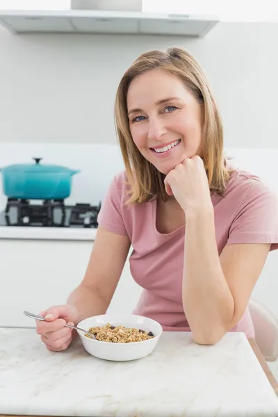 Mujer sonriente teniendo cereales en la cocina —  Fotos de Stock