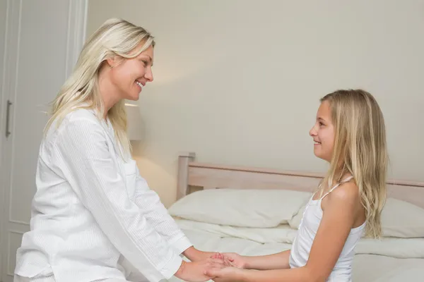 Mor och dotter håller hand i sängen — Stockfoto