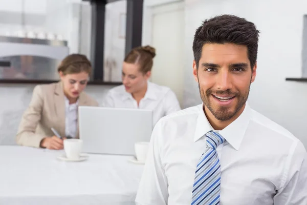 Empresário sorridente com colegas na mesa de escritório — Fotografia de Stock