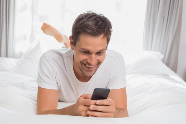 Jonge man van het tekstoverseinen in bed thuis — Stockfoto