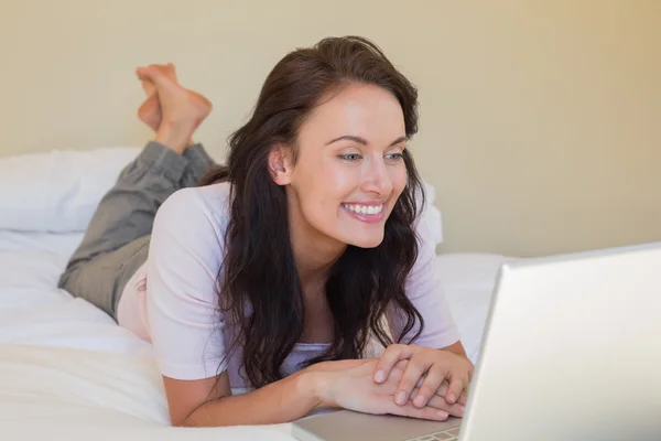 Woman using laptop while lying in bed — Stock Photo, Image