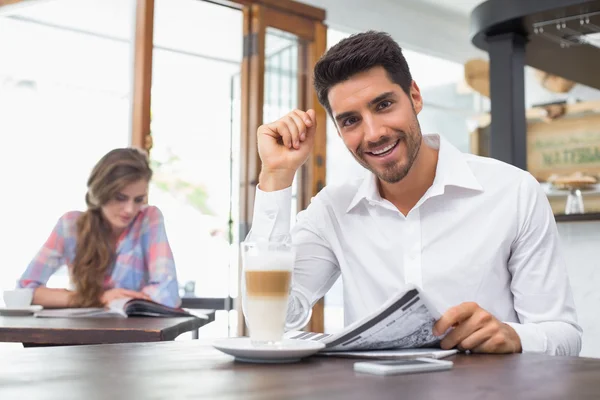 Lächelnder Mann liest Zeitung im Café — Stockfoto