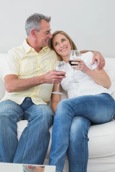 Pareja relajada con copas de vino sentada en el sofá —  Fotos de Stock