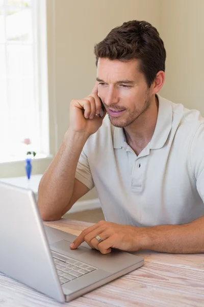 Man die thuis laptop en mobiele telefoon gebruikt — Stockfoto