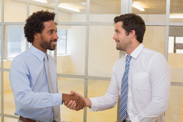 Усміхнені бізнесмени тремтять руками в офісі — стокове фото
