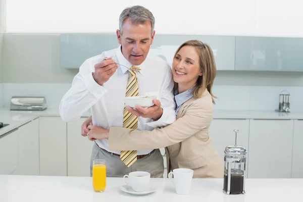 Mujer abrazando al hombre mientras desayuna en la cocina —  Fotos de Stock