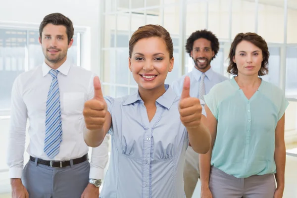 Businesswoman with colleagues gesturing thumbs up — Stock Photo, Image