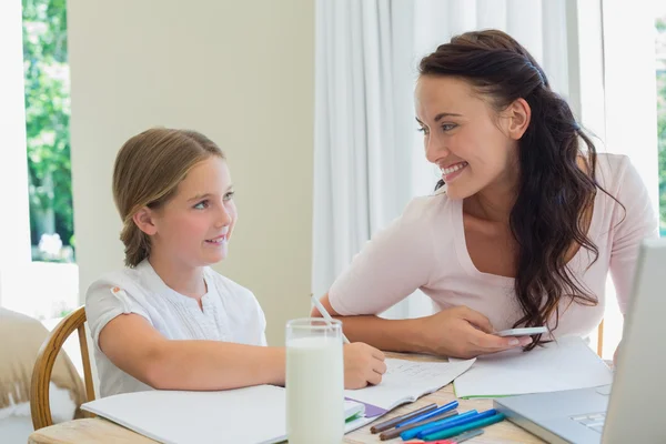 Donna guardando figlia che studia a tavola — Foto Stock