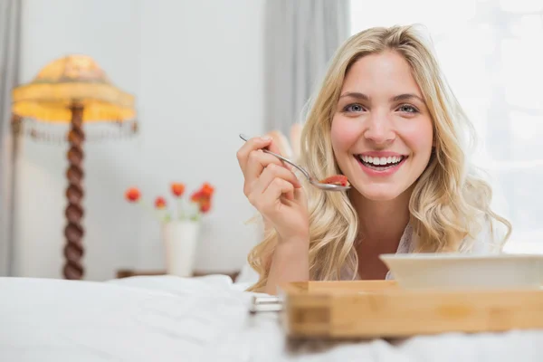 Glückliche Gelegenheitsfrau mit Essen im Bett — Stockfoto