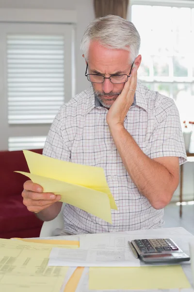 Homem sério sentado com contas em casa e calculadora — Fotografia de Stock
