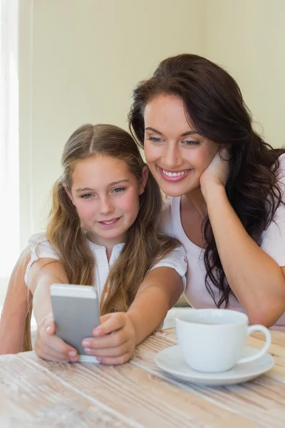 Daughter with mother taking self portrait through mobile phone — Stock Photo, Image