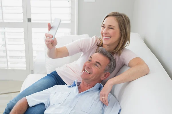 Casal clicando fotos com telefone celular em casa — Fotografia de Stock