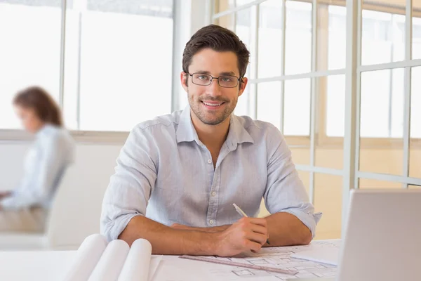 Glimlachend zakenman bezig met blauwdrukken op kantoor — Stockfoto