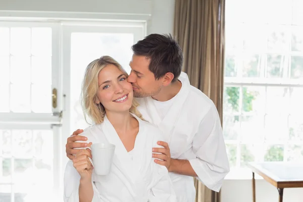 Loving young man kissing woman's cheek at home — Stock Photo, Image