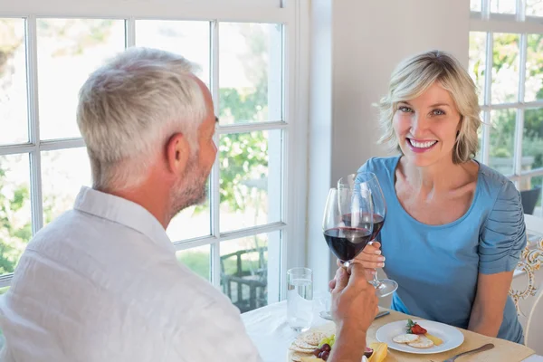 Porträt eines reifen Paares beim Anstoßen auf Weingläser beim Essen — Stockfoto