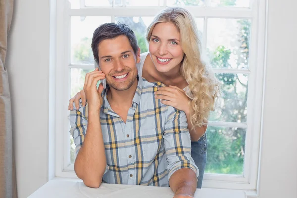 Man op oproep naast een mooie vrouw thuis — Stockfoto