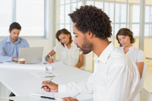 Geschäftsmann schreibt Dokument mit Kollegen in Besprechung — Stockfoto