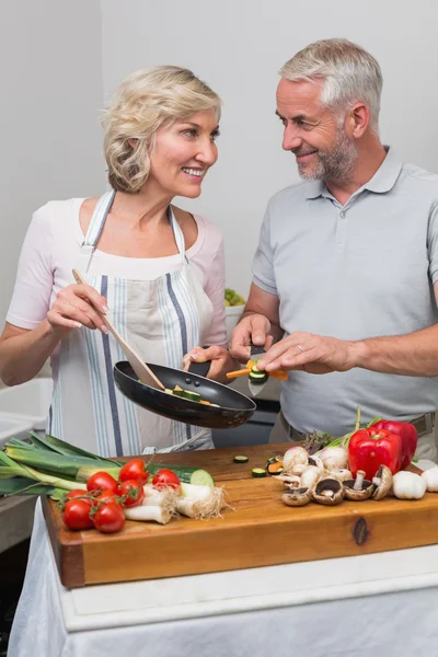 Зрелая пара готовит еду вместе на кухне — стоковое фото