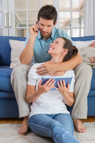 Pareja usando tableta digital y teléfono celular en la sala de estar —  Fotos de Stock