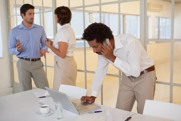 Uomo d'affari che utilizza laptop e cellulare con i colleghi — Foto Stock