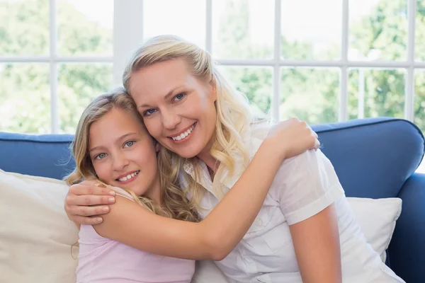 Matka i córka przytulanie siebie na kanapie — Zdjęcie stockowe