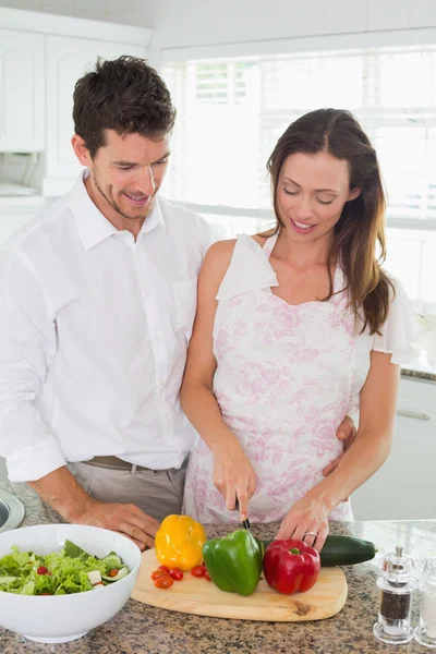 Jeune couple coupant des légumes dans la cuisine — Photo