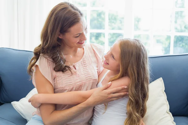 Mãe abraçando sua filha feliz na sala de estar — Fotografia de Stock