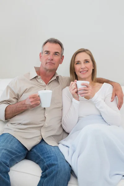 Relajada pareja amorosa con tazas de café en la sala de estar —  Fotos de Stock