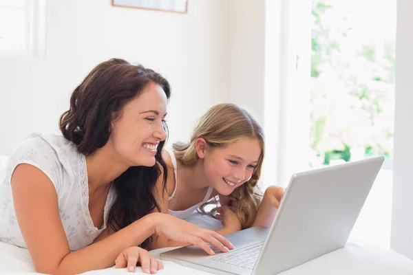 Kvinna med dotter med laptop i sängen — Stockfoto