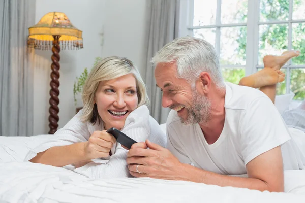 Cheerful mature couple reading text message at home — Stock Photo, Image