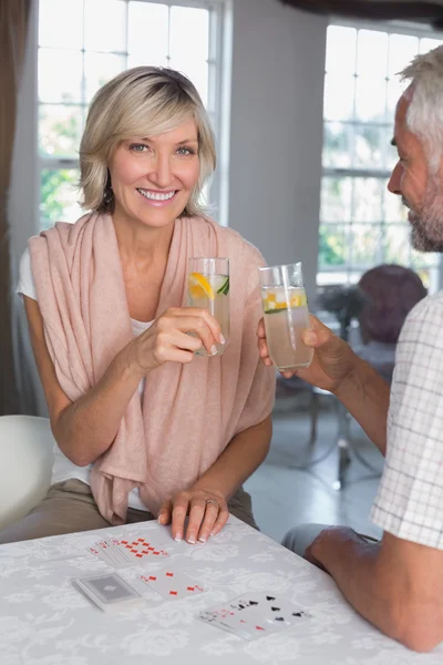 Pareja madura brindando bebidas mientras juega a las cartas —  Fotos de Stock