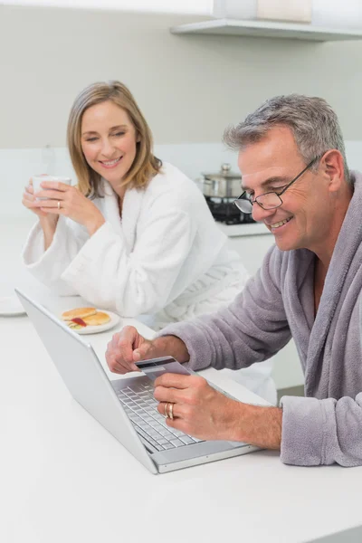 Happy couple in bathrobe doing online shopping at home — Stock Photo, Image