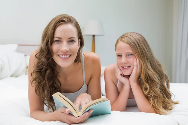 Girl and mother with book lying in bed — Stock Photo, Image