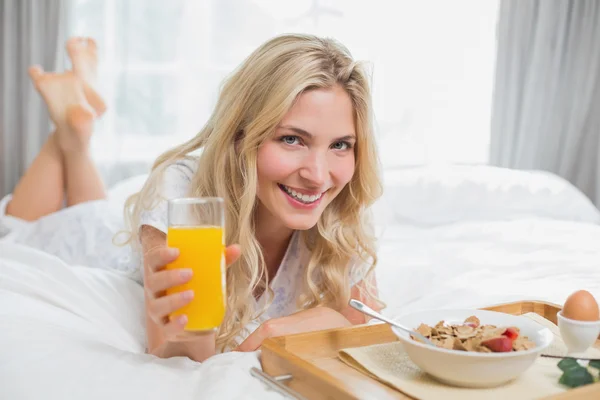Glückliche junge Frau frühstückt im Bett — Stockfoto