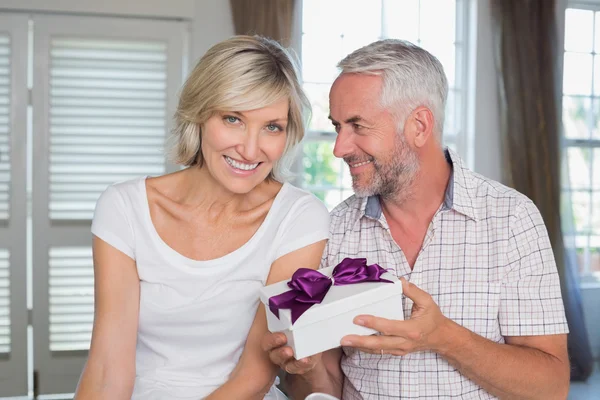 Glückliches älteres Paar mit einem Geschenkkarton zu Hause — Stockfoto