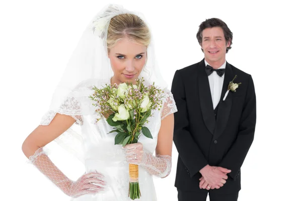 Невеста нюхает цветы, а жених стоит на заднем плане — стоковое фото
