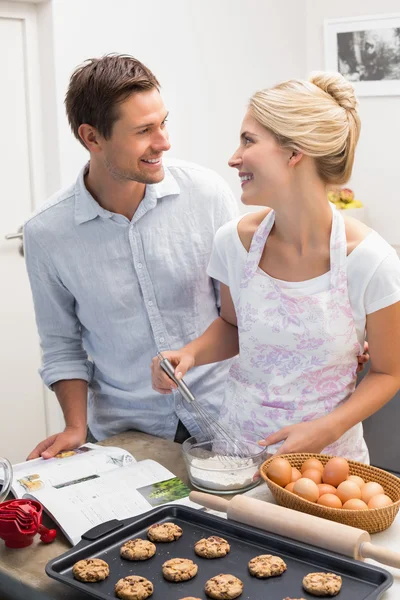 Happy young couple preparing cookies in kitchen — Stock Photo, Image