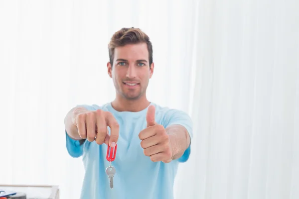 Uomo tenendo fuori la nuova chiave di casa mentre gesticolando pollici verso l'alto — Foto Stock