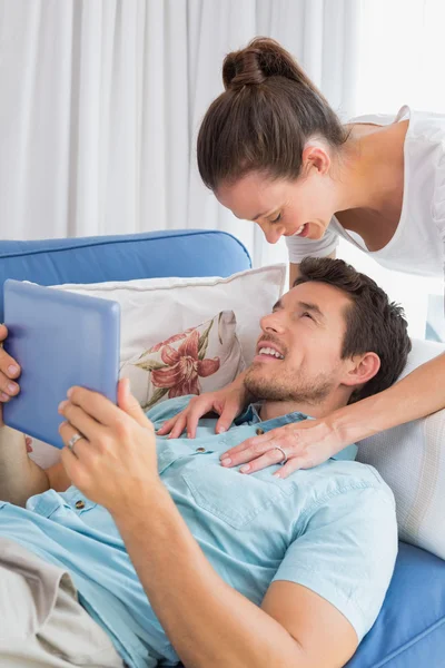 Loving couple with digital tablet in living room — Stock Photo, Image