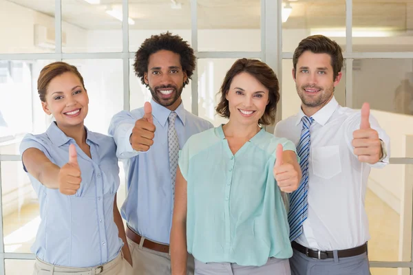 Business colleagues gesturing thumbs up in office — Stock Photo, Image